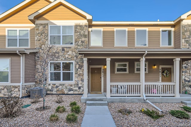 view of front facade featuring a porch, cooling unit, and stone siding