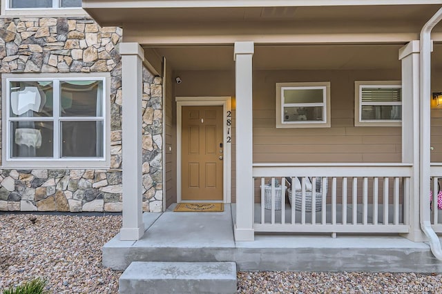 entrance to property with a porch and stone siding