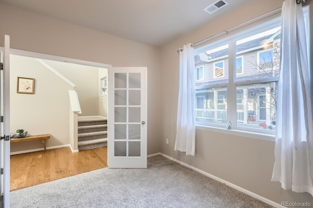 empty room featuring visible vents, baseboards, carpet floors, stairs, and french doors