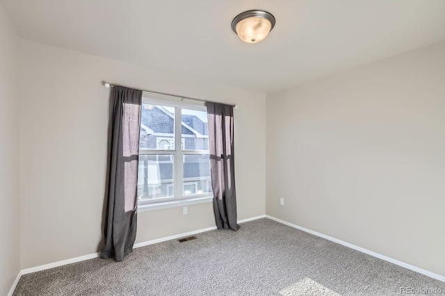 empty room with carpet flooring, baseboards, and visible vents