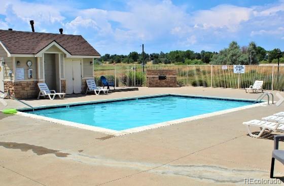 community pool with a patio area and fence
