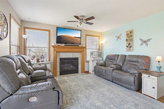 living room featuring ceiling fan and a tile fireplace