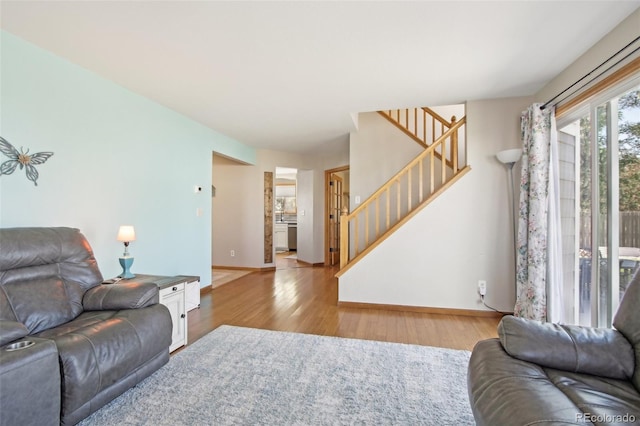 living room featuring baseboards, stairway, and light wood-style floors