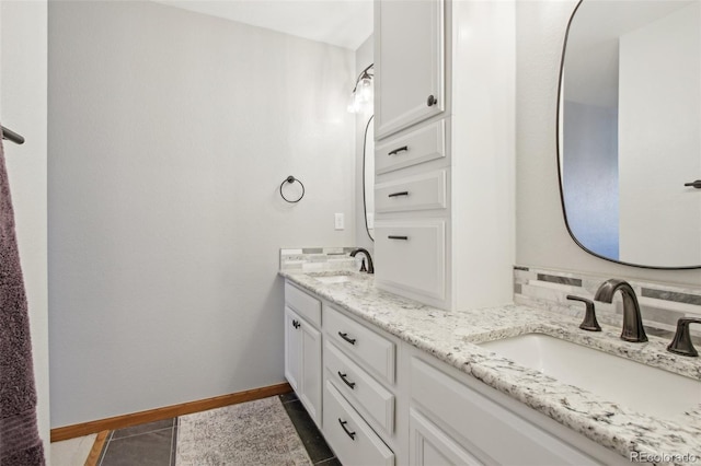 bathroom featuring double vanity, baseboards, a sink, and tile patterned flooring