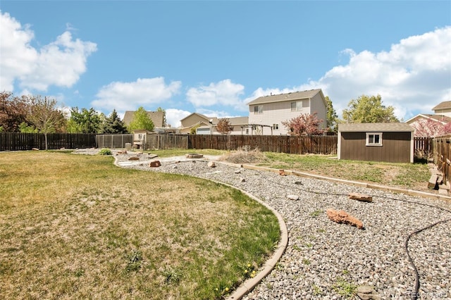 view of yard featuring a fenced backyard, a shed, an outbuilding, and a residential view