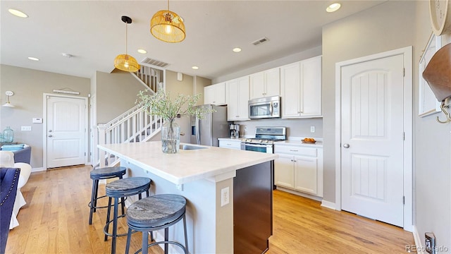 10016 Hough Pt, Parker, CO 80134 - kitchen with appliances with stainless steel finishes, light wood-style floors, a kitchen bar, a sink, and white cabinets