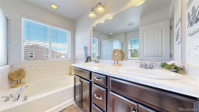 10016 Hough Pt, Parker, CO 80134 - bathroom featuring double vanity, a garden tub, a shower with door, and wood finished floors