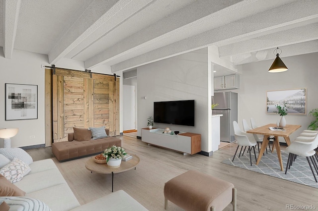 living area with baseboards, beamed ceiling, a barn door, light wood-style floors, and a textured ceiling