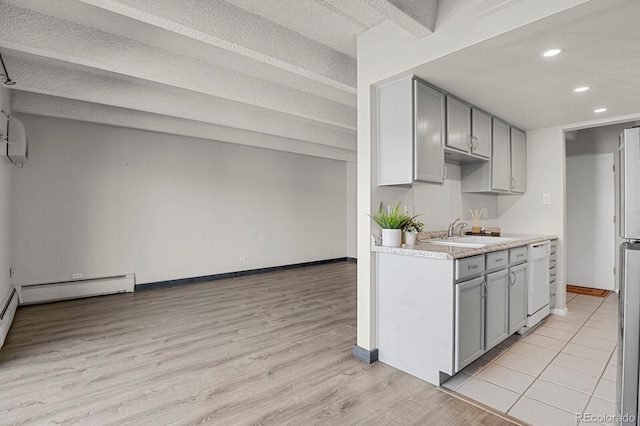 kitchen featuring a sink, light countertops, light wood-style flooring, and gray cabinetry