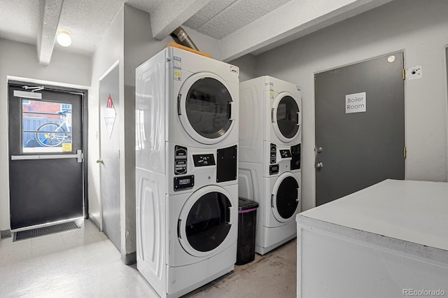 laundry area with a textured ceiling and stacked washing maching and dryer