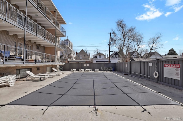 view of swimming pool featuring a residential view, a patio, and fence