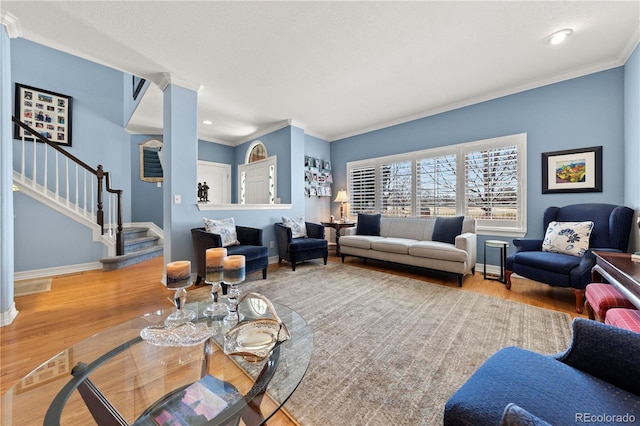 living area featuring stairway, baseboards, wood finished floors, and ornamental molding