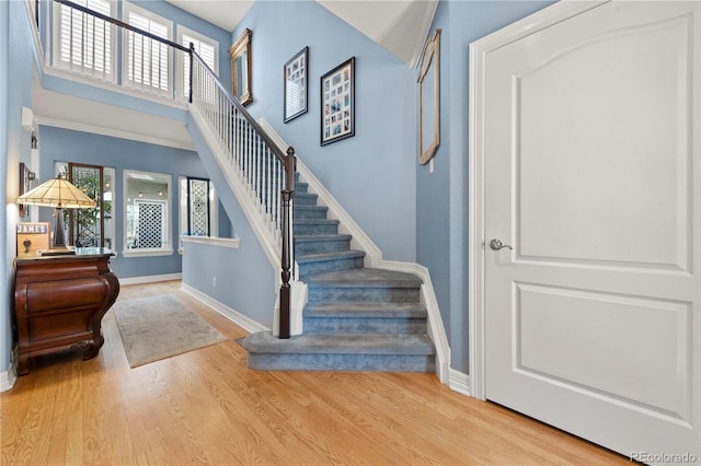 staircase featuring plenty of natural light, a towering ceiling, and wood finished floors