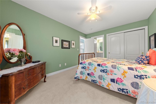 carpeted bedroom with a closet, ceiling fan, ensuite bath, and baseboards