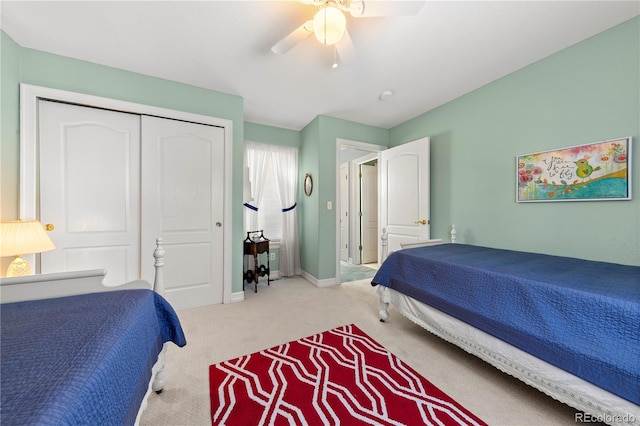 carpeted bedroom with a closet, baseboards, and a ceiling fan