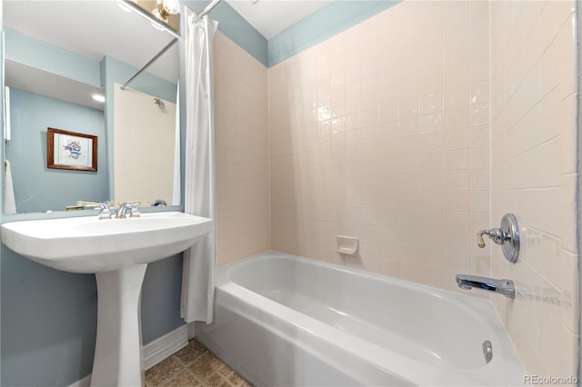 bathroom featuring tile patterned floors, shower / bath combo with shower curtain, baseboards, and a sink