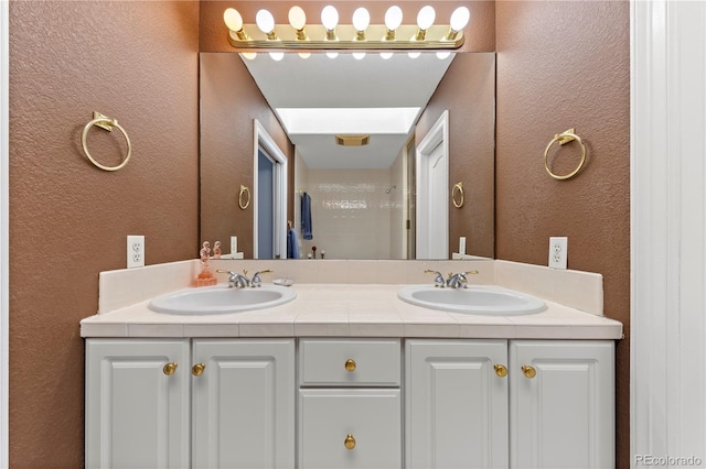 bathroom with double vanity, a textured wall, and a sink