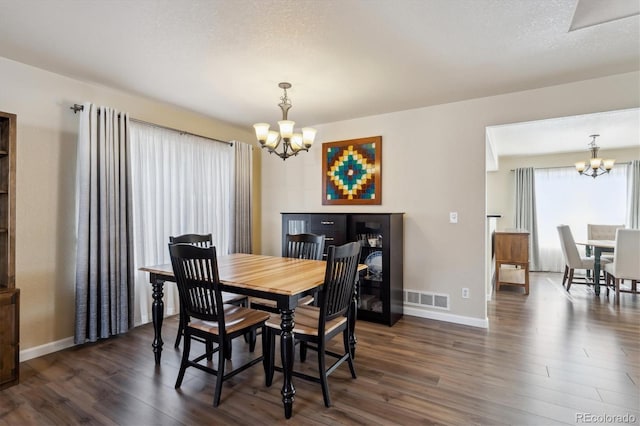 dining space with dark hardwood / wood-style flooring, a textured ceiling, and a chandelier