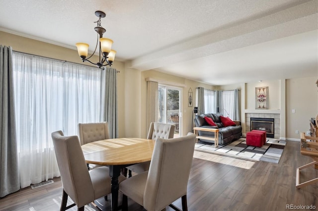 dining area featuring hardwood / wood-style flooring, a fireplace, a textured ceiling, and a notable chandelier