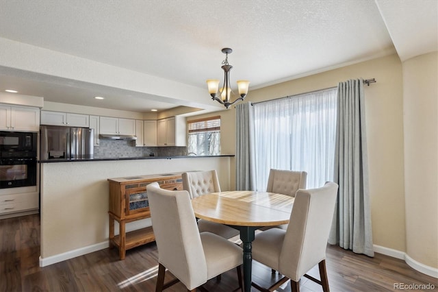 dining space featuring dark wood-type flooring, a notable chandelier, and a textured ceiling