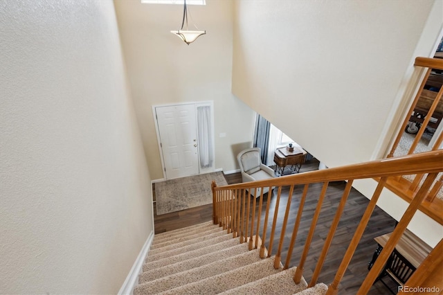 stairs with hardwood / wood-style flooring and a towering ceiling