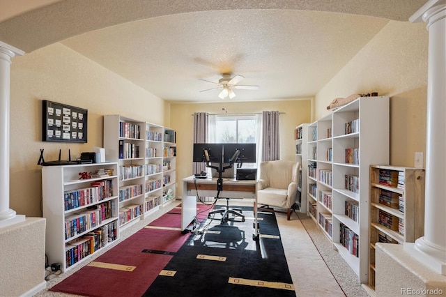 carpeted home office with ceiling fan, decorative columns, and a textured ceiling