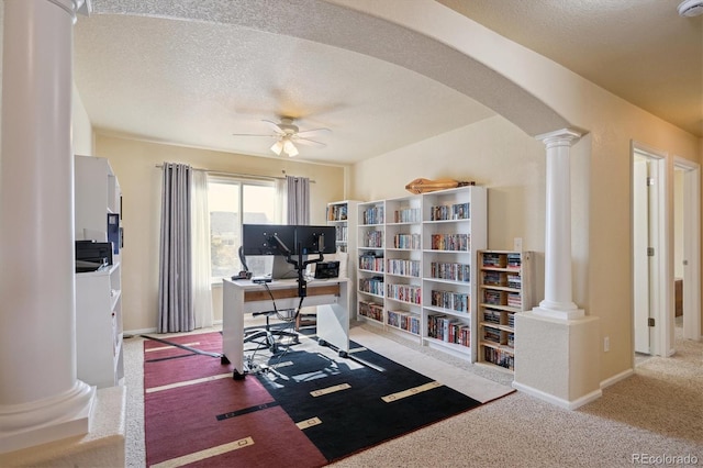 carpeted office space featuring ceiling fan, a textured ceiling, and ornate columns