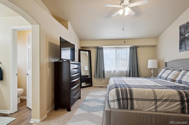 carpeted bedroom with lofted ceiling, multiple windows, ceiling fan, and ensuite bathroom