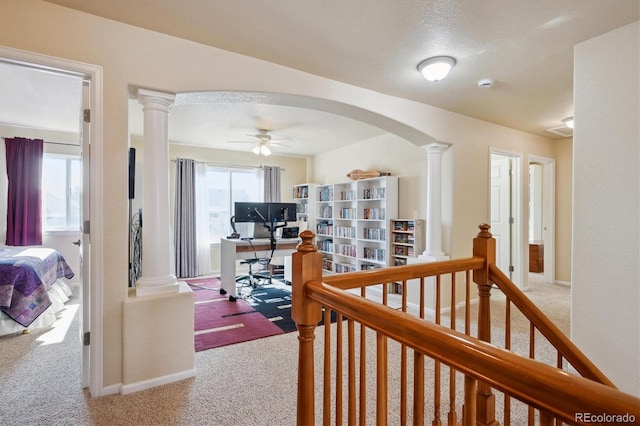 hall with carpet flooring, a textured ceiling, and ornate columns