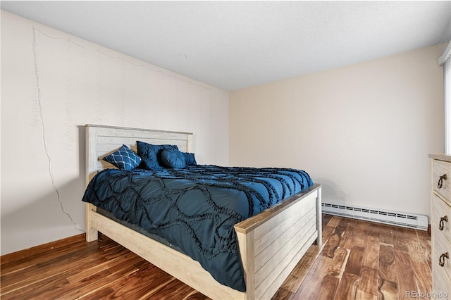 bedroom with dark hardwood / wood-style floors and a baseboard heating unit