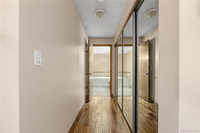 hall with a textured ceiling and hardwood / wood-style flooring