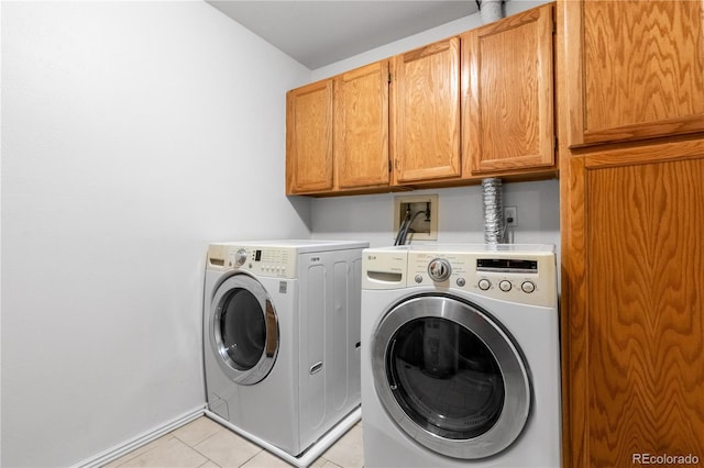 clothes washing area with cabinets, light tile patterned floors, and washing machine and dryer