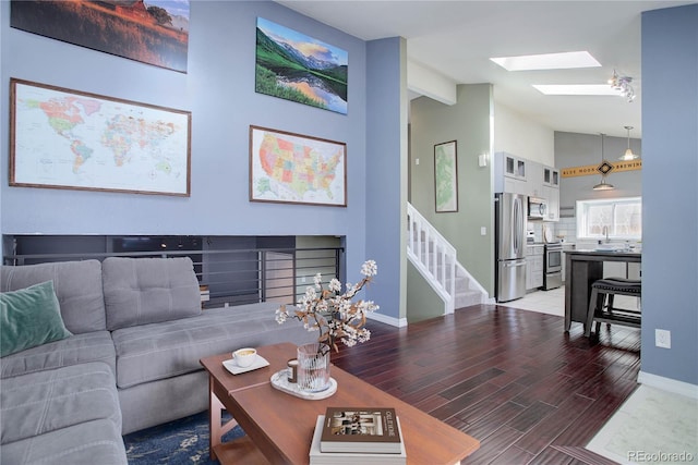 living room with wood-type flooring, high vaulted ceiling, and a skylight