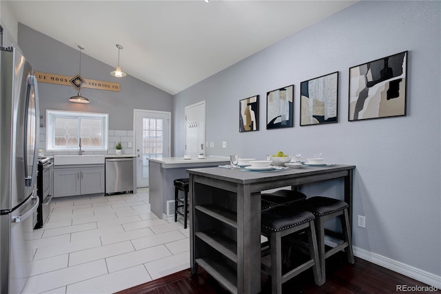 kitchen featuring stainless steel appliances, decorative light fixtures, a breakfast bar, and kitchen peninsula