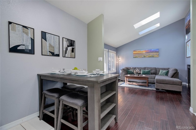 dining area featuring hardwood / wood-style flooring and lofted ceiling with skylight