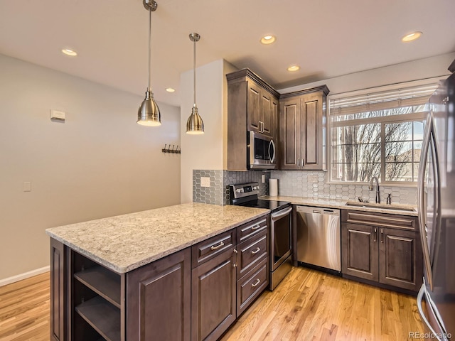 kitchen with appliances with stainless steel finishes, decorative light fixtures, sink, kitchen peninsula, and dark brown cabinets