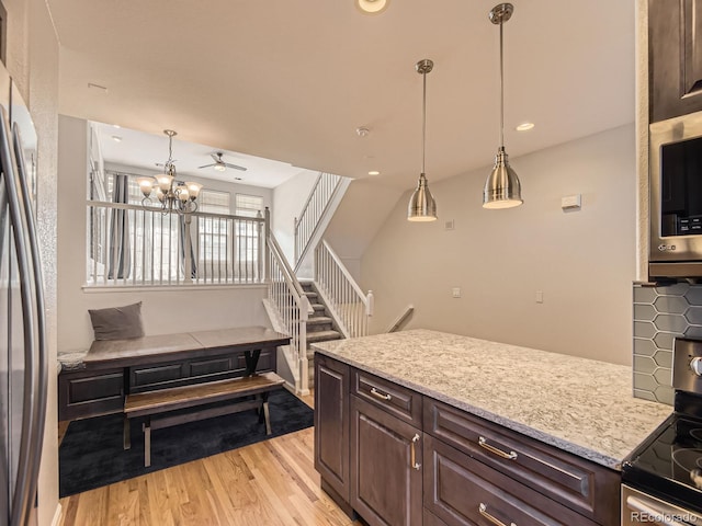 kitchen featuring stainless steel appliances, hanging light fixtures, dark brown cabinets, and light hardwood / wood-style floors