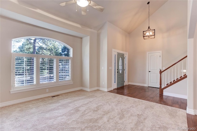 entrance foyer featuring dark wood finished floors, visible vents, stairway, high vaulted ceiling, and ceiling fan with notable chandelier