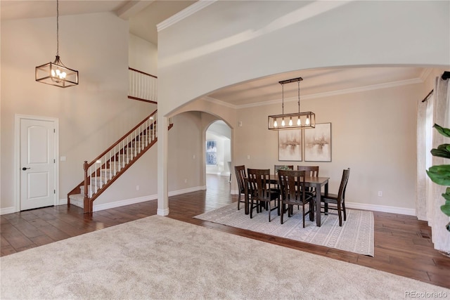 dining area with stairs, arched walkways, wood finished floors, and a chandelier