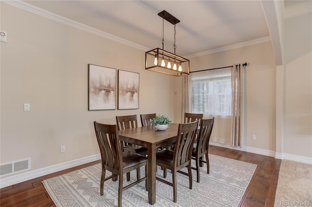 dining space featuring baseboards, hardwood / wood-style flooring, visible vents, and crown molding