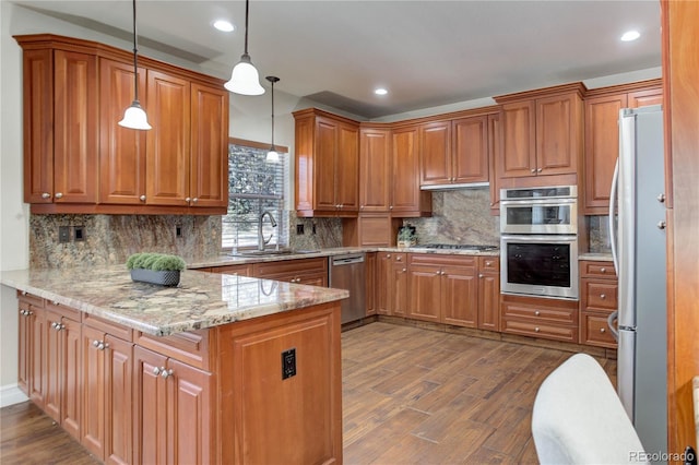 kitchen featuring a peninsula, appliances with stainless steel finishes, brown cabinets, and a sink