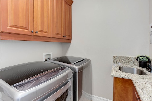 washroom featuring cabinet space, baseboards, washer and clothes dryer, and a sink