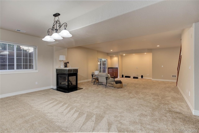 living area featuring carpet floors, a premium fireplace, visible vents, and baseboards