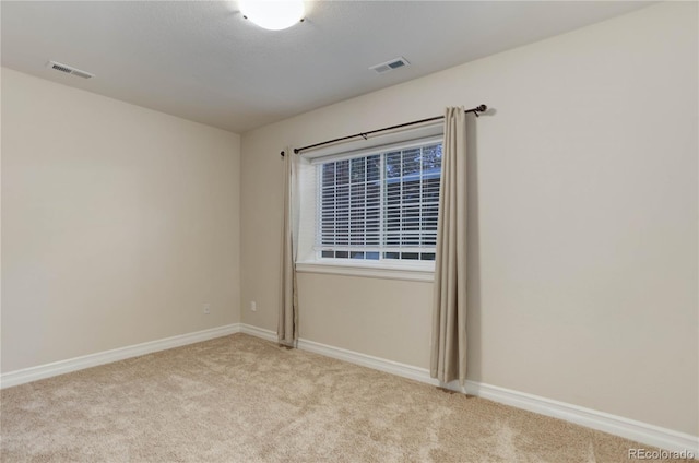 spare room with carpet, visible vents, and baseboards