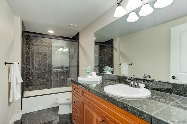 full bathroom featuring double vanity, visible vents, bath / shower combo with glass door, toilet, and a sink