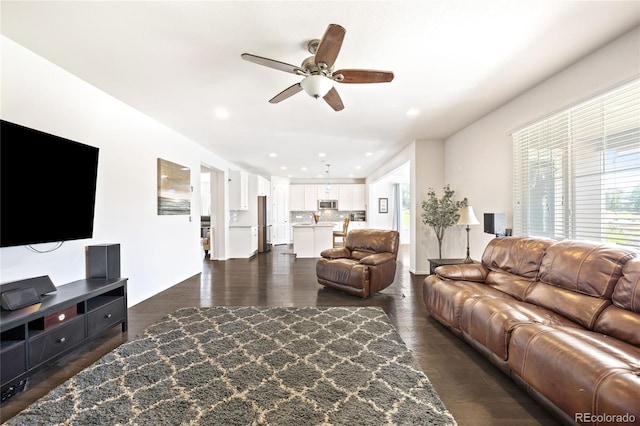 living room featuring ceiling fan and dark hardwood / wood-style floors