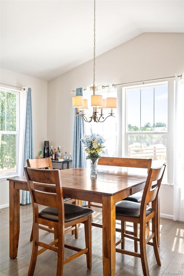 dining space with vaulted ceiling, an inviting chandelier, and hardwood / wood-style floors