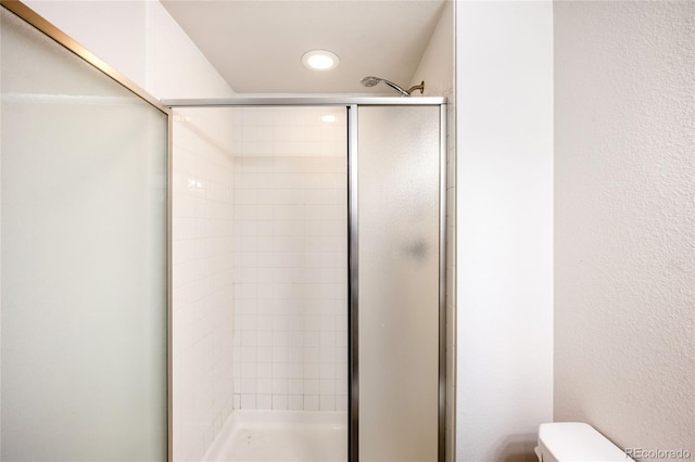 bathroom with a shower with door and toilet