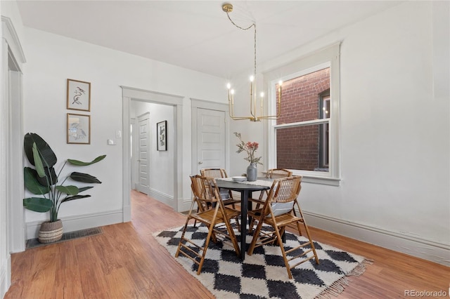 dining area featuring light wood-type flooring and a notable chandelier