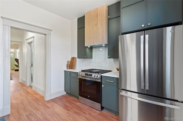 kitchen with blue cabinetry, decorative backsplash, light hardwood / wood-style floors, and appliances with stainless steel finishes